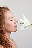Woman smelling white lily with eyes closed