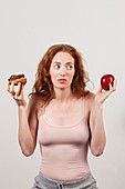 Portrait of woman holding apple and doughnut