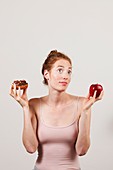 Portrait of woman holding apple and doughnut