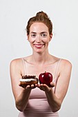 Smiling woman holding apple and doughnut