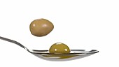 Olives falling on spoon, slow motion
