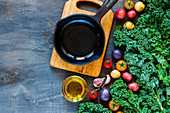 Vintage cast iron skillet and fresh colorful organic vegetables for healthy eating on rustic wooden background