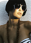 A young, short-haired woman wearing sunglasses and a necklace