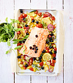 Mediterranean salmon on a baking tray with olives and tomatoes