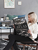 Woman sitting in living room reading atlas
