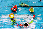 Food frame of olive oil, balsamic vinegar, vegetables, herbs and spices on turquoise vintage background