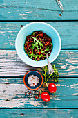 Healthy salad with quinoa, tomato and arugula on turquoise vintage table
