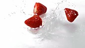 Strawberries falling in water, slow motion
