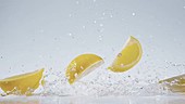 Lemon pieces falling in water, slow motion