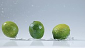 Three limes falling in water, slow motion