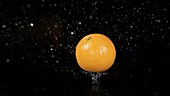 Orange falling in water, slow motion