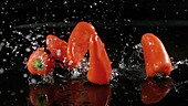Peppers falling in water, slow motion