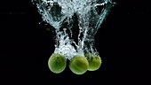 Three limes falling in water, slow motion