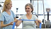 Physiotherapist and patient using resistance band