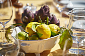 Fresh lemons and artichokes in a bowl on a table laid outside