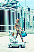 Blonde Frau neben Miniaturwagen mit 'Roboter'