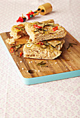 Focaccia with chilli and rosemary sliced on a wooden board