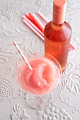 A slushy Frosé in a cocktail glass with a bottle of rosé wine