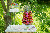 Ananas mit Erdbeeren gespickt und Windlicht auf Gartentisch