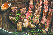 Ribeye-Steak in Streifen geschnitten mit Mangochutney auf Holzschneidebrett (Aufsicht)
