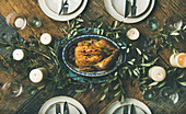 Flat-lay of whole roasted chicken in tray for Christmas eve celebration over rustic wooden background, top view