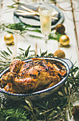 Christmas or New Year celebration table setting: Roast chicken, plates, silverware, glass and toy holiday decoration