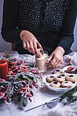Frau taucht Dinkelplätzchen in Milchkaffee (weihnachtlich)
