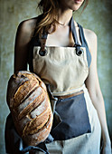 Young woman holding in her hand a fresh loaf of italian bread