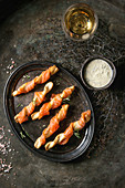 Appetizer with smoked salmon on crispy breadsticks served on vintage metal tray with cheese dill sauce