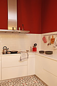 Modern white kitchen with red walls and patterned floor