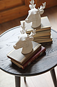 Zwei Bücherstapel mit Hirschköpfen aus Steingut auf rundem Tischchen