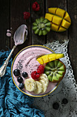 A smoothie bowl with raspberry yoghurt, fresh fruit and poppy seeds