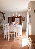 Arrangement of roses on festively set table below chandelier in dining area