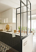 Halboffene Küche mit halbhoher Glaswand als Raumteiler