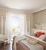Schlafzimmer in gedeckten Farben mit offener Tür zum Balkon