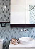 Wash basin with countertop basin, above it a wall tap and mirror cabinet, 3D tile pattern
