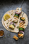 Grilled halloumi skewers with zucchini and red onions on flatbread