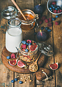 Healthy vegan breakfast, Oatmeal granola with bottled almond milk, honey, fresh fruit and berries on hoard over rustic wooden table background