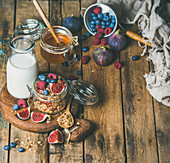 Healthy breakfast, Oatmeal granola with bottled almond milk, honey, fresh fruit and berries on hoard over rustic wooden table