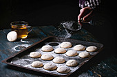 Homemade almond cookies on old oven tray and cup of hot tea over dark blue wooden table