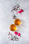 Zwei Tassen Tee mit Rosenblüten und Herzplätzchen zum Valentinstag
