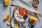 Soya yogurt with blood oranges, dark chocolate and crushed walnuts served in a bowl
