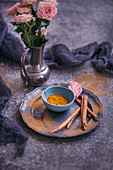 Turmeric powder in a small blue bowl and cinnamon sticks on a grey plate