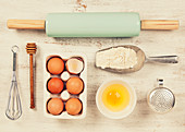 Baking tools and ingredients - flour, rolling pin, eggs, measuring spoons on vintage wood table