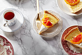 Slices of soft cheesecake with caramelized red oranges and whipped cream served on plates