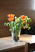 Tulpen und Äste in einer Glasvase mit Kieselsteinen