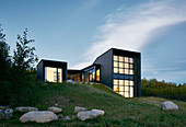 Kubisches Architektenhaus am Abend mit beleuchteten Glasfronten