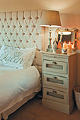 Small chest of drawers next to bed with button-tufted headboard