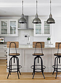 Industrial-style barstools at kitchen island with white base units