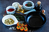 Stillleben mit Olivenöl, Balsamico-Essig, Mörser, verschiedenen bunten Gewürzen und Gemüse